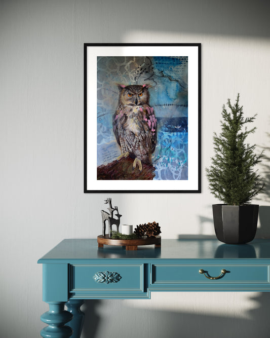 Framed owl artwork on a wall above a blue table with decorative items.