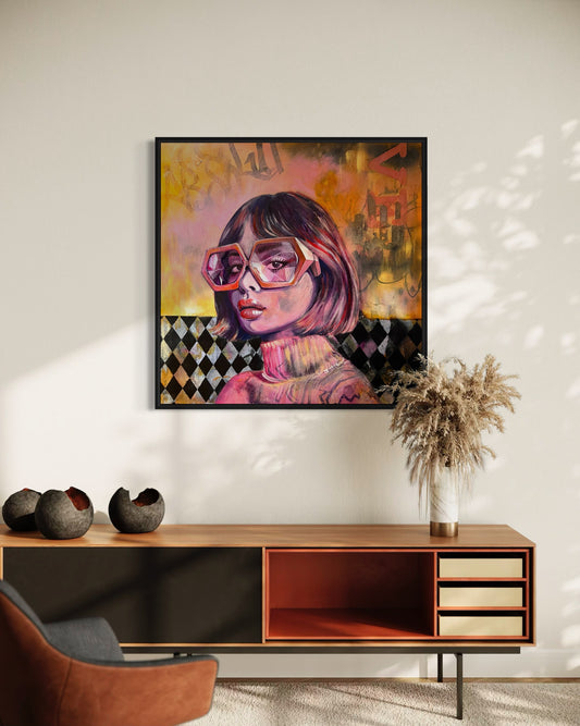 Framed artwork of a woman with sunglasses on a wall above a wooden console table.