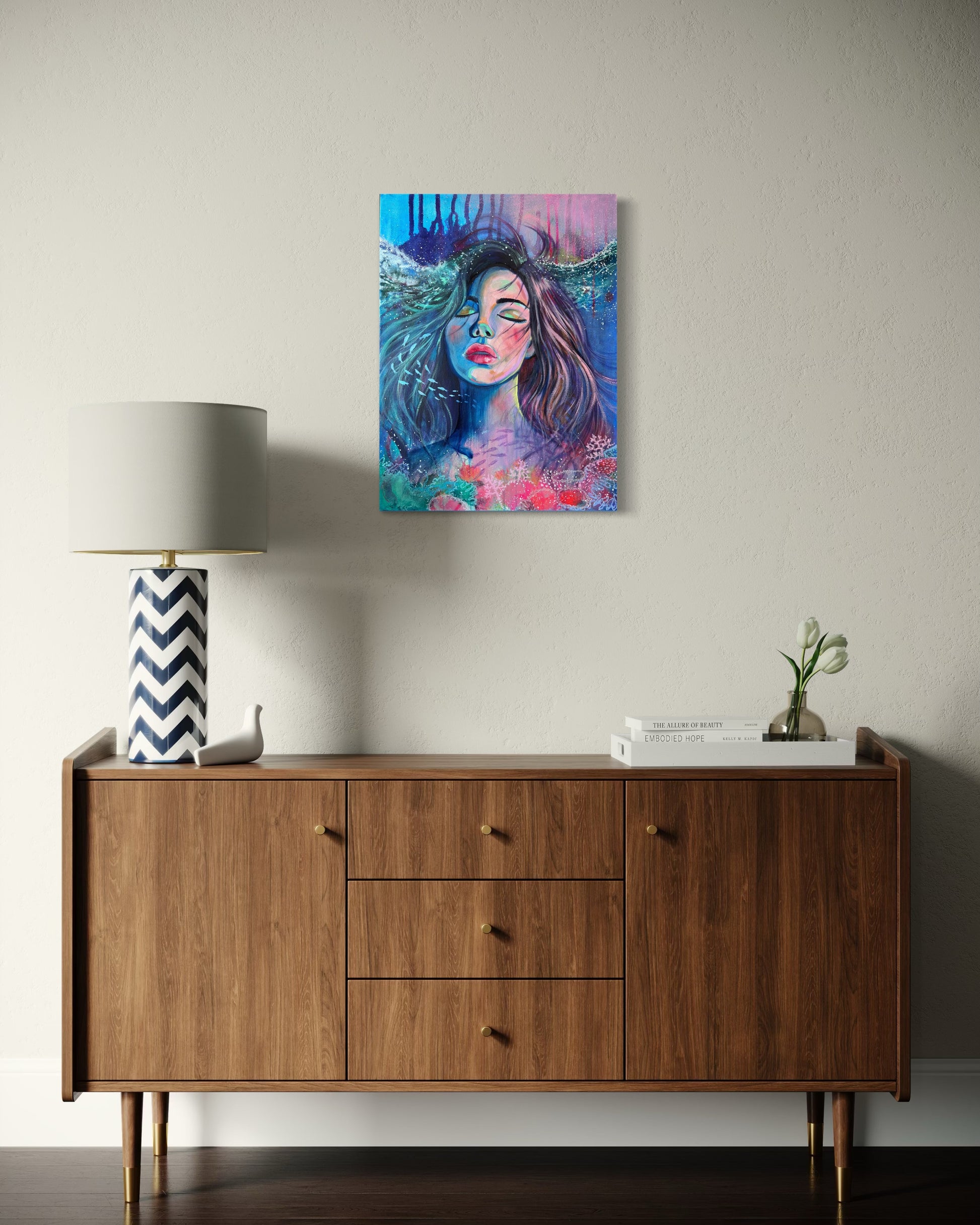 Blue and modern portrait artwork of a woman with long hair in an underwater setting on a wall above a retro wooden sideboard.