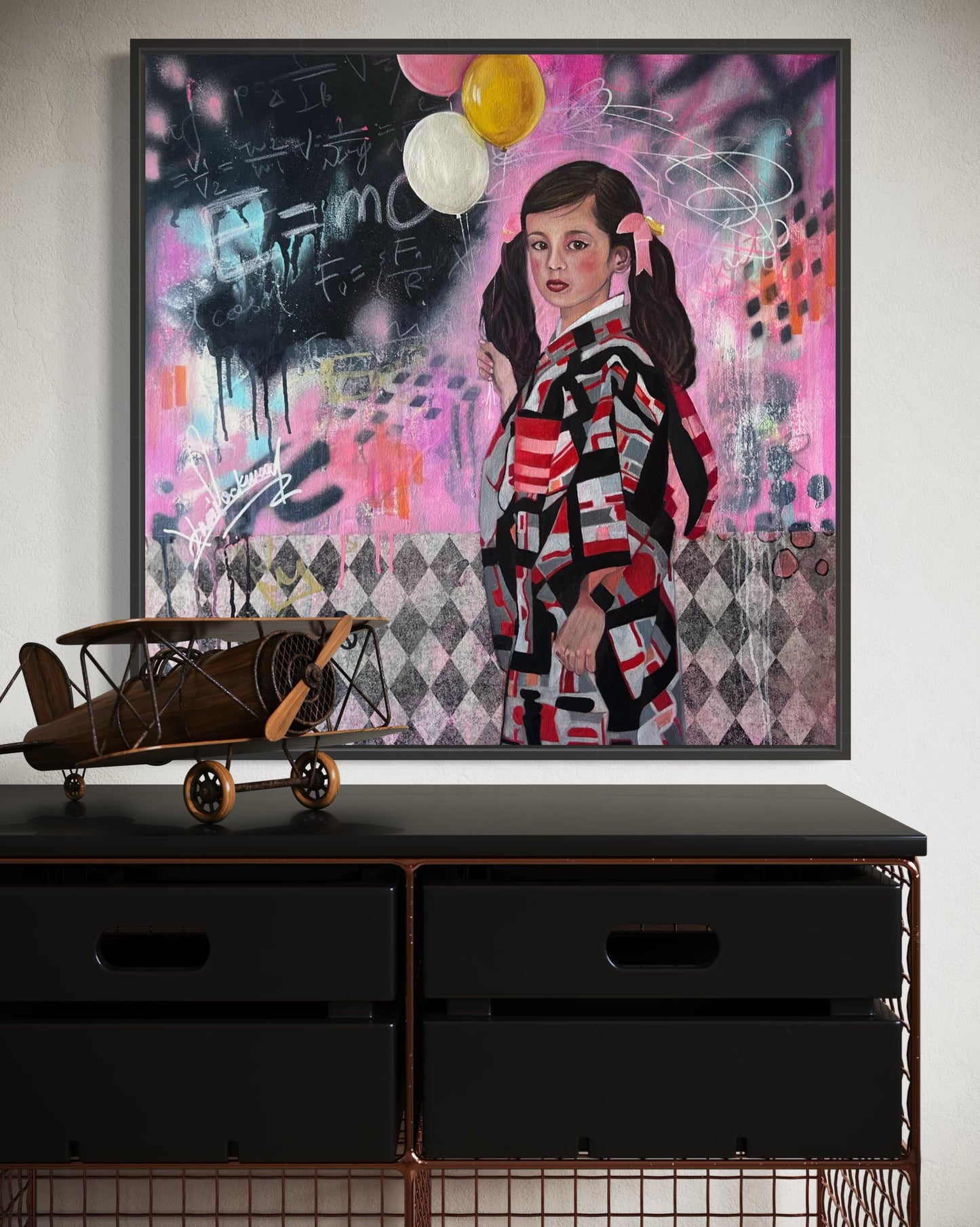 Framed artwork of a person in a colorful outfit with abstract elements on a wall above a black dresser.