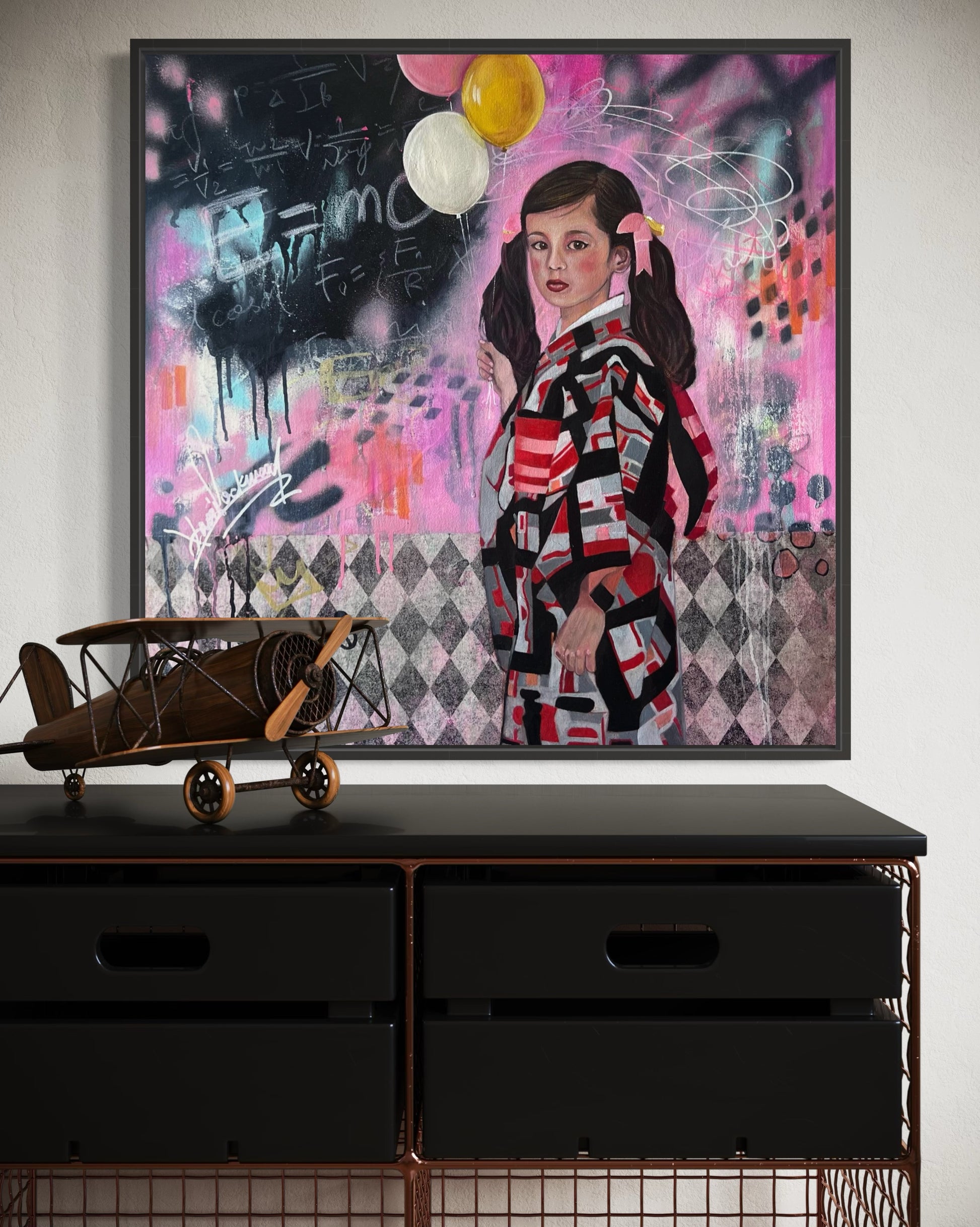 Framed artwork of a person in a colorful outfit with abstract elements on a wall above a black dresser.
