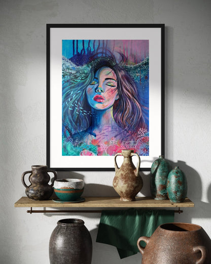 Framed blue and modern portrait artwork of a woman with long hair in an underwater setting on a wall above a shelf with rustic vases.